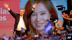 Peronist presidential candidate Alberto Fernández waves to supporters in front of a large image of his running mate, former President Cristina Fernández, in Buenos Aires, Argentina, Sunday, Oct. 27, 2019. 