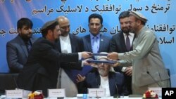 Wakil pemerintah Afghanistan Attaurahman Saleem (kiri) dan perwakilan kelompok Gulbuddin Hekmatyar, Amin Karim bertukar dokumen pasca penandatanganan perjanjian damai di Kabul, Afghanistan, Kamis (22/9) lalu. 