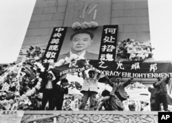 中国学生在北京天安门广场上的人民英雄纪念碑前展示胡耀邦像和“民主之光耀邦”等标语（1989年4月19日）