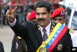 Venezuela's President Nicolas Maduro flashes a victory sign to supporters as he arrives to the Supreme Court to deliver his annual state of the nation report in Caracas, Venezuela, Sunday, Jan. 15, 2017.