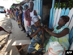 FILE - A health worker administers a yellow fever vaccine to a woman on August 27, 2008 on a roadside in Koumassi, a poor quartier of Abidjan after a case was discovered of yellow fever.
