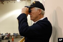 An observer watches an employees at the Palm Beach County Supervisor of Elections office feed ballots through a machine as he counts votes during a recount, Nov. 14, 2018, in West Palm Beach, Florida.