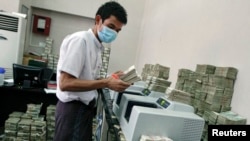 FILE - An employee counts Myanmar kyat banknotes in a bank in Yangon, April 5, 2012. The United States said on Wednesday it was ready to relax some sanctions on Myanmar.