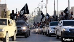 FILE - Islamic State fighters parade on military vehicles along the streets of Syria's northern Raqqa province.