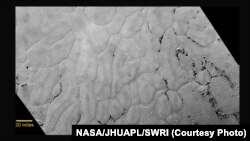 In the center left of Pluto’s vast heart-shaped feature lies a vast, craterless plain that appears to be no more than 100 million years old, and is possibly still being shaped by geologic processes. 