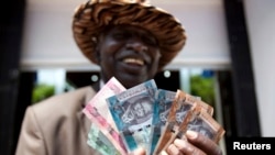Un homme du Soudan du Sud présente de nouveaux billets de banque à l'extérieur de la Banque centrale du Soudan du Sud à Juba, le 18 juillet 2011.