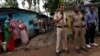 Police stand guard as residents (L) look on at the Ravidas camp, the slum where three of the four men convicted of raping and murdering a 23-year-old woman in Delhi reside at, in New Delhi, September 13, 2013.