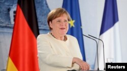 German Chancellor Angela Merkel, left and French President Emmanuel Macron talk in the garden of Meseberg Castle, the German government's guest house in Meseberg, Germany, June 29, 2020.