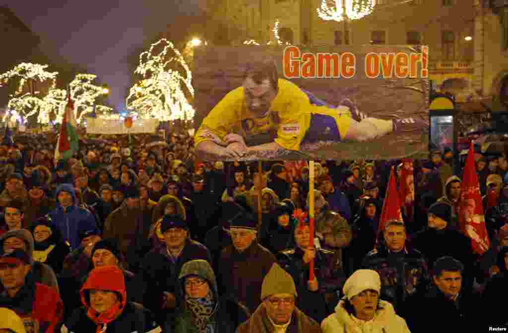 Seorang perempuan memegang plakat yang menampilkan Perdana Menteri Hungaria Viktor Orban sebagai pemain sepak bola dalam protes anti-pemerintah yang dilakukan oleh kelompok-kelompok-kelompok sipil di Budapest. Protes itu mengikuti sejumlah aksi unjuk rasa lainnya melawan pemerintahan Orban, yang telah&nbsp; jatuh popularitas dalam beberapa bulan terakhir. &nbsp;