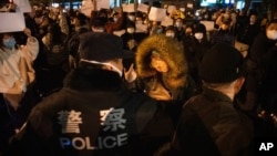 2022年11月27日，警察在北京街头和手举白纸的抗议者对峙。