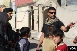 Captain Raad Qasim of the Iraqi Army's Najaf battalion asks children to go inside briefly while nearby gunfire is heavy, Nov. 20, 2016. (H. Murdock/VOA)