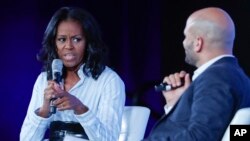 Former first lady Michelle Obama talks with Sam Kass, former White House chef and senior policy adviser for nutrition, at the Partnership for a Healthier America 2017 Healthier Future Summit in Washington, May 12, 2017