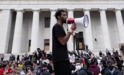 Protesters listen to a man speak as they gather peacefully in front of the Ohio Statehouse in Downtown Columbus, Ohio, June 1, 2020, to protest the death of George Floyd.