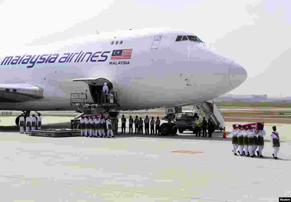 The remains of the passengers of downed Malaysia Airlines MH17 are carried from the transport plane during a repatriation ceremony, in Sepang, Aug. 22, 2014.