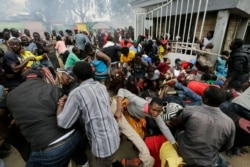FILE - Residents desperate for a planned distribution of food for those suffering under Kenya's coronavirus-related movement restrictions push through a gate and create a stampede, at a district office in the Kibera slum of Nairobi, April 10, 2020.