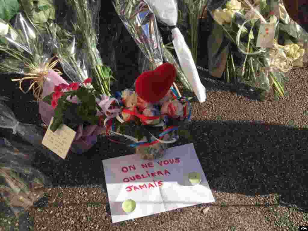 Sign next to flowers left to honor Bastille Day attack victims says "We Will Never Forget" in Nice, France, July 2016. (Photo: VOA Persian Service)