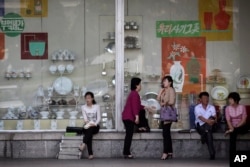 People sit in front of a window display of household items at a department store in Pyongyang, North Korea, June 2, 2016.