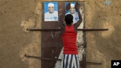 Young man glues campaign posters for Ibrahim Boubacar Keita on top of a pair posters for rival Dramane Dembele, Gao, Mali, July 25, 2013.