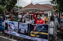 Pengungsi Afghanistan memegang spanduk dan plakat dalam aksi protes terkait status pencari suaka di Surabaya, 11 November 2021. (Foto oleh Juni Kriswanto / AFP)