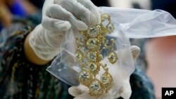 FILE - In this Nov. 24, 2015, file photo, a Bureau of Customs appraiser shows to the media a set of jewelry from Roumeliotes Collection, one of three sets of the Marcos Jewelry Collection, during appraisal at the Central Bank of the Philippines, in Manila, Philippines.