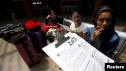 FILE - A Colombian health worker gives travellers information on how to prevent the spread of the Zika virus, at the main bus terminal in Bogota, Colombia, Jan. 31, 2016.