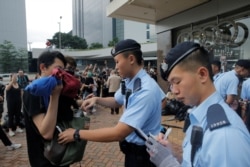A police officer checks the bag of a pedestrian following a day of violence over an extradition bill that would allow people to be sent to mainland China for trial, in Hong Kong, China June 13, 2019.