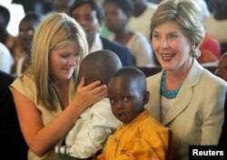 FILE - United States first lady Laura Bush and daughter Jenna, left, hold Rwandan children they met at an AIDS project during a church service at Kagarama Church in Kigali, July 14, 2005. Bush was on the last leg of her official visit to Africa after the meeting of G8 leaders in Gleneagles, Scotland.