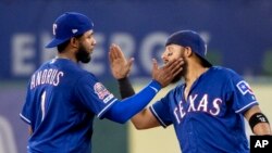 FILE - Texas Rangers baseball players Elvis Andrus (left) and Rougned Odor playfully slap each other to celebrate their 5-0 win over the Houston Astros in a baseball game, July 11, 2019, in Arlington, Texas. (AP Photo/Jeffrey McWhorter)
