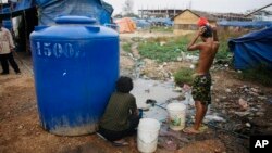 រូបឯកសារ៖ ពលរដ្ឋ​ម្នាក់​ងូត​ទឹក​នៅ​ក្បែរ​ផ្ទះ​របស់​ខ្លួន​ នៅ​ក្នុង​តំបន់​ក្រីក្រ​នៅ​ជាយ​រាជធានី​ភ្នំពេញ​នៅ​ថ្ងៃទី ១៩ ខែកុម្ភៈ ឆ្នាំ២០០៩។ (AP)