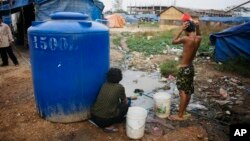 រូបឯកសារ៖ ពលរដ្ឋ​ម្នាក់​ងូត​ទឹក​នៅ​ក្បែរ​ផ្ទះ​របស់​ខ្លួន​ នៅ​ក្នុង​តំបន់​ក្រីក្រ​នៅ​ជាយ​រាជធានី​ភ្នំពេញ​នៅ​ថ្ងៃទី ១៩ ខែកុម្ភៈ ឆ្នាំ២០០៩។ (AP)