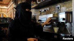 FILE - A veiled woman makes coffee as she works at a coffee shop in Tabuk, Saudi Arabia.