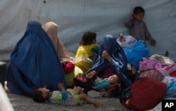 FILE - Afghan refugee families wait at the office of United Nations High Commissioner for Refugees to register to go back to Afghanistan, in Peshawar, Pakistan, April 27, 2017.