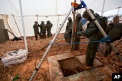 FILE - Israeli soldiers stand around the opening of a hole that leads to a tunnel that the army says crosses from Lebanon to Israel, near Metula, Dec. 19, 2018.
