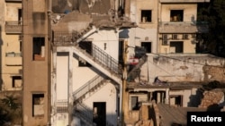 A Lebanese flag hangs in front of the buildings that were damaged by an explosion at the Beirut port, in the neighborhood of Karantina, Lebanon, Aug. 13, 2020. 