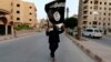 A militant loyal to the Islamic State in Iraq and the Levant (ISIL) waves an ISIL flag in Raqqa, Syria, June 29, 2014. 