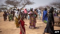 FILE - Refugees walk in a camp for internally displaced persons, in northern Burkina Faso, June 20, 2021.