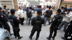 FILE - Cambodian riot police officers stand guard at the main gate of the Phnom Penh Municipal Court, in Phnom Penh, Cambodia, Aug. 15, 2015.