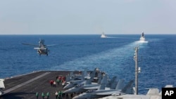 FILE - In this Nov. 19, 2019, photo, made available by the U.S. Navy, a helicopter lifts off from the aircraft carrier USS Abraham Lincoln as it transits the Strait of Hormuz. 