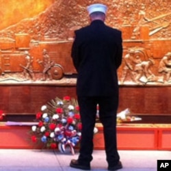 An honor guard pay his respect at the bronze firefighter memorial at the World Trade Center site in New York, September 11, 2011