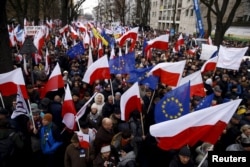 File - People hold European Union and Polish national flags during an anti-government demonstration in front of the Constitutional Court in Warsaw, Poland, Dec. 12, 2015.