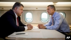 Ukrainian President Petro Poroshenko, left, and NATO Secretary General Jens Stoltenberg talk in a helicopter on the way to a military training ground outside Lviv, western Ukraine, Sept. 21, 2015. 