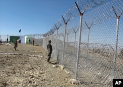 Pakistani soldiers stand guard at a fence between Pakistan and Afghanistan at Angore Adda, Pakistan, Oct. 18, 2017. Pakistan's military says the fencing and guard posts along the border with Afghanistan help prevent militant attacks.