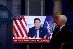 Vice President Mike Pence, right, and President Donald Trump watch a video of New York Governor Andrew Cuomo speaking, during a coronavirus task force briefing at the White House, April 19, 2020, in Washington.