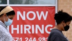FILE - Women walk past by a Now Hiring sign outside a store in Arlington, Virginia, Aug. 16, 2021. The Labor Department has reported about $87 billion in unemployment benefits could have been paid improperly, with a significant portion attributable to fraud.
