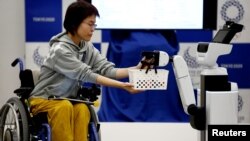 Toyota's Human Support Robot (HSR) delivers a basket to a woman in a wheelchair at a demonstration of Tokyo 2020 Robot Project for Tokyo 2020 Olympic Games in Tokyo, Japan.