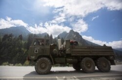 An Indian army soldier gestures towards the photographer as his convoy moves on the Srinagar- Ladakh highway at Gagangeer, northeast of Srinagar, Indian-controlled Kashmir, Sept. 1, 2020.