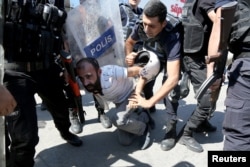 FILE - Riot police detain a demonstrator during a protest against the suspension of teachers from classrooms over alleged links with Kurdish militants, in the southeastern city of Diyarbakir, Turkey, Sept. 9, 2016.