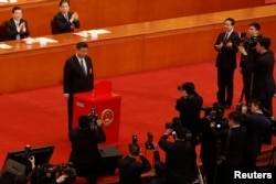 Chinese President Xi Jinping pauses after casting his ballot during a vote on a constitutional amendment lifting presidential term limits, at the third plenary session of the National People's Congress (NPC) at the Great Hall of the People in Beijing.