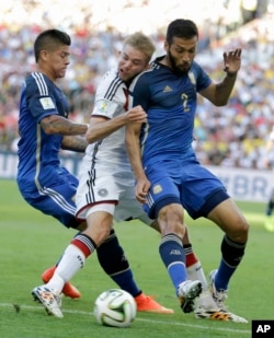 Germany's Christoph Kramer gets hit in the face by Argentina's Ezequiel Garay shoulder (2) while pinned between Garay and Marcos Rojo during the World Cup final soccer match.