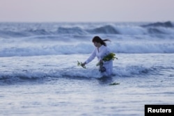 지난 3월 동일본 대지진 12주년을 맞아 후쿠시마현 이와키 해변에서 한 주민이 희생자들을 추모하기 위한 꽃을 바다에 띄우고 있다.
